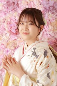 ファーストコレクション本庄早稲田店のスタジオのピンクのお花をバックにポーズをとっている振袖を着た女性。成人式の前撮り撮影会の様子