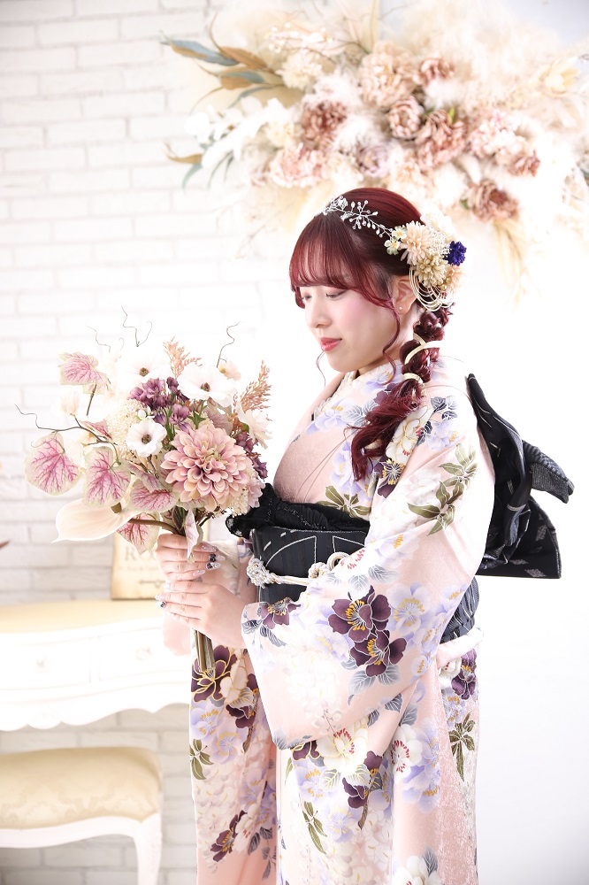 くすみピンクの振袖を着てお花を持つ成人式前撮りの二十歳の女性