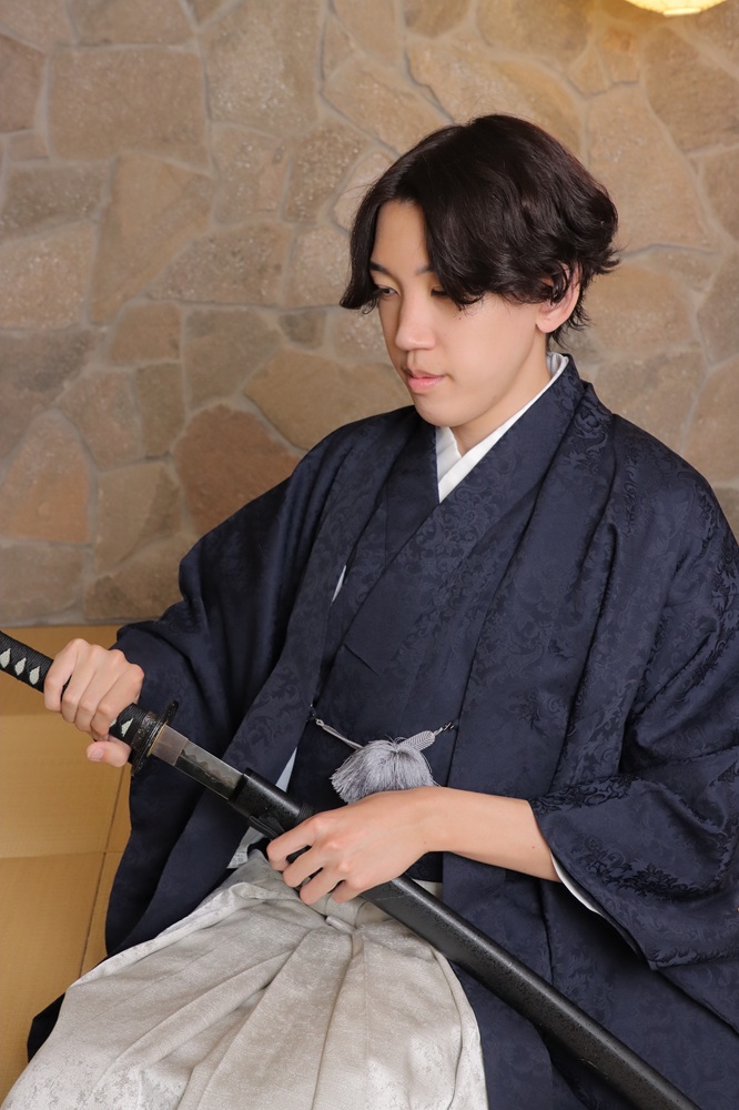 黒い羽織、グレーの成人男子袴をきた男性